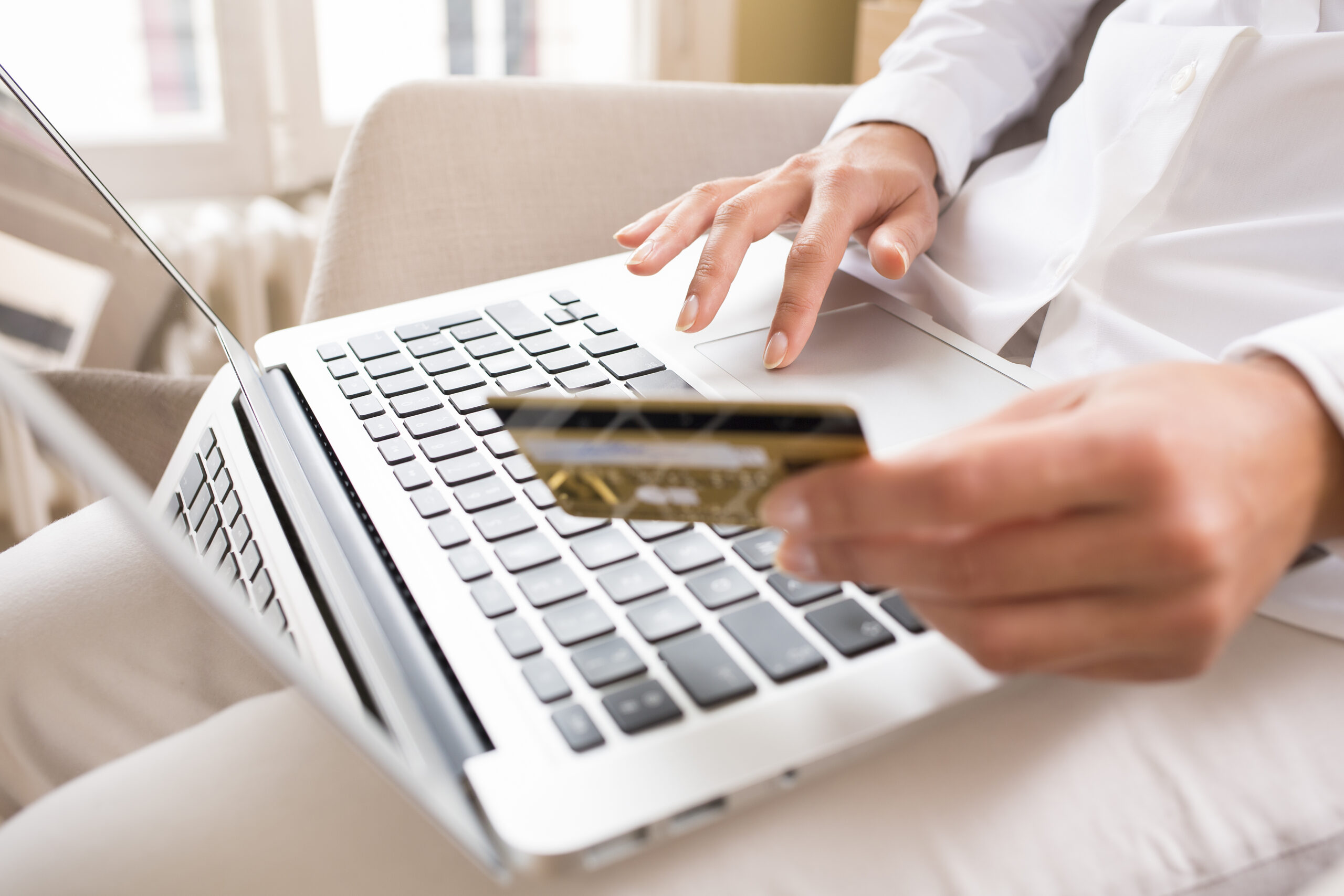 Close-up woman's hands holding a credit card and using computer
